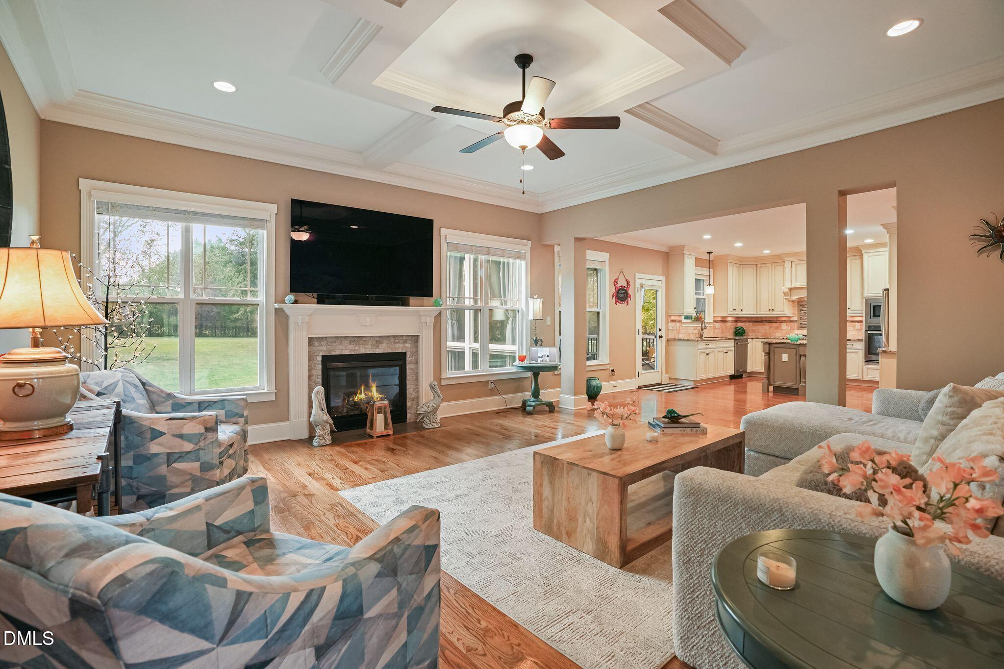 Furnished living room with a tray ceiling, fireplace, and open view into the kitchen.