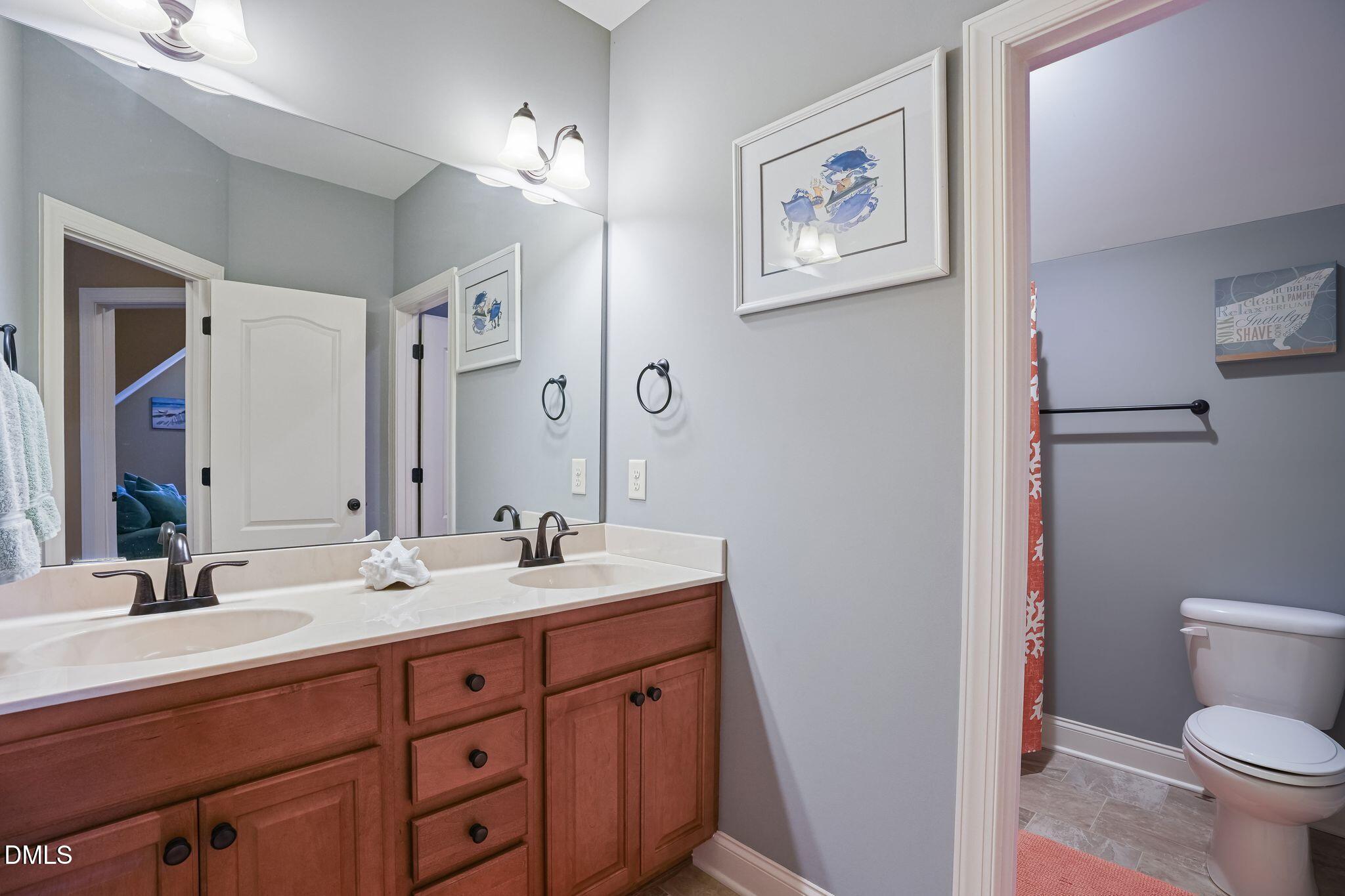 Bathroom with a double-sink wood vanity and a separate toilet area.