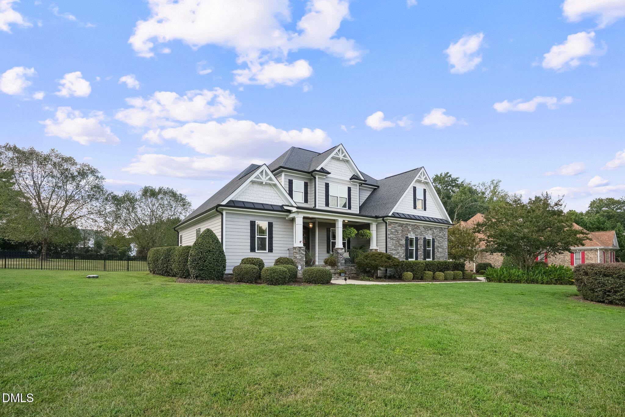 Two-story gray house with stone accents, a covered porch, and a broad green lawn.