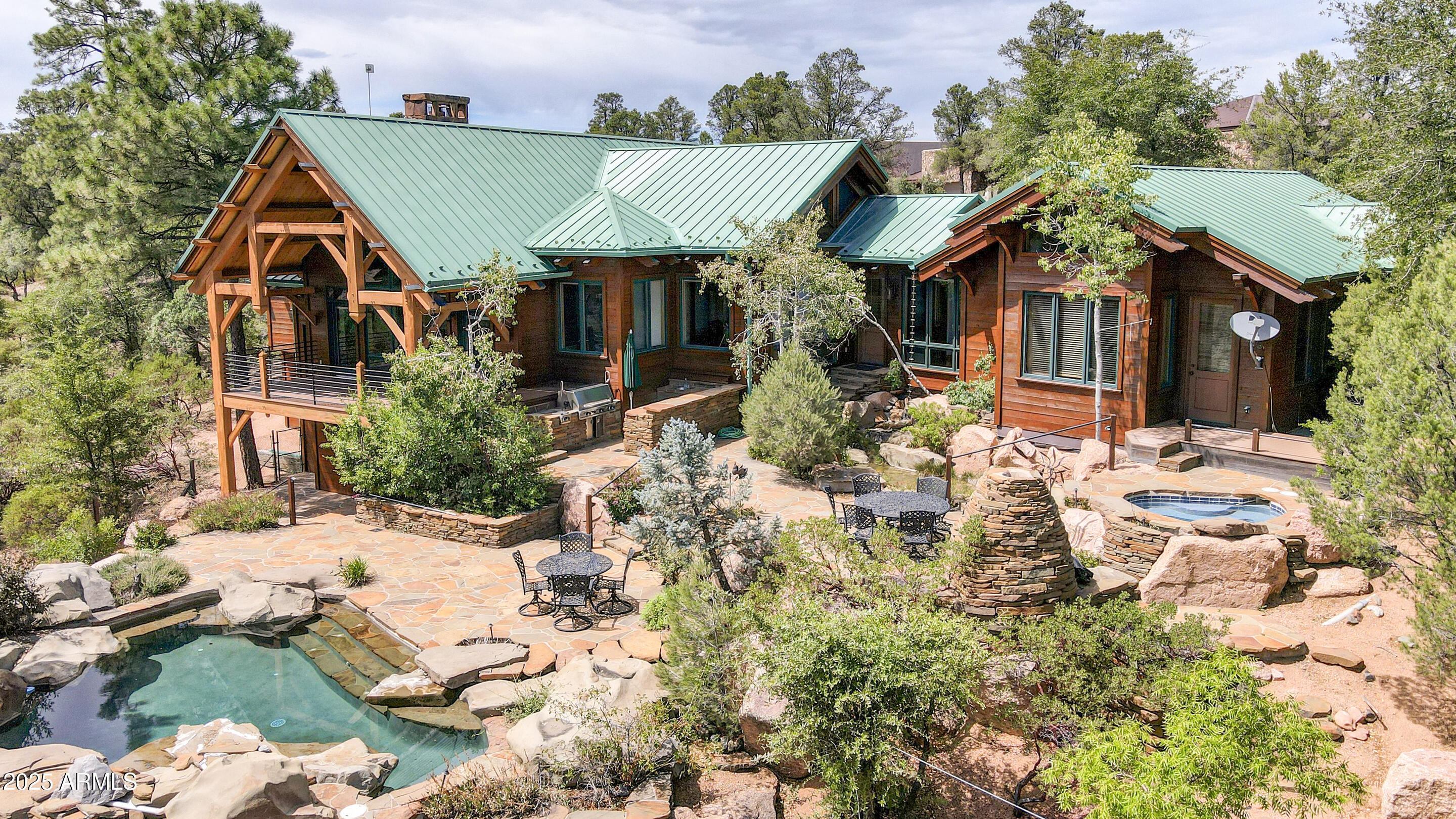 Wood-sided home with a green metal roof, timber porch, and landscaped patio with a pool.