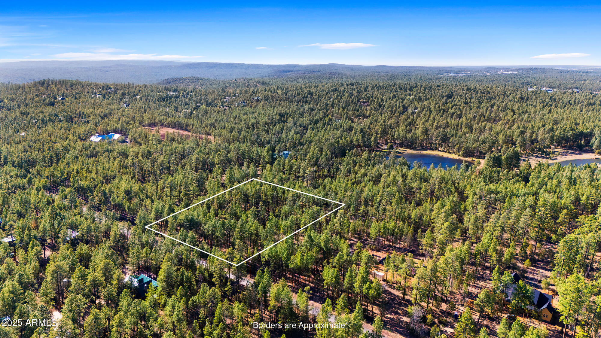Aerial view of a wooded parcel outlined in white, with a small lake nearby.