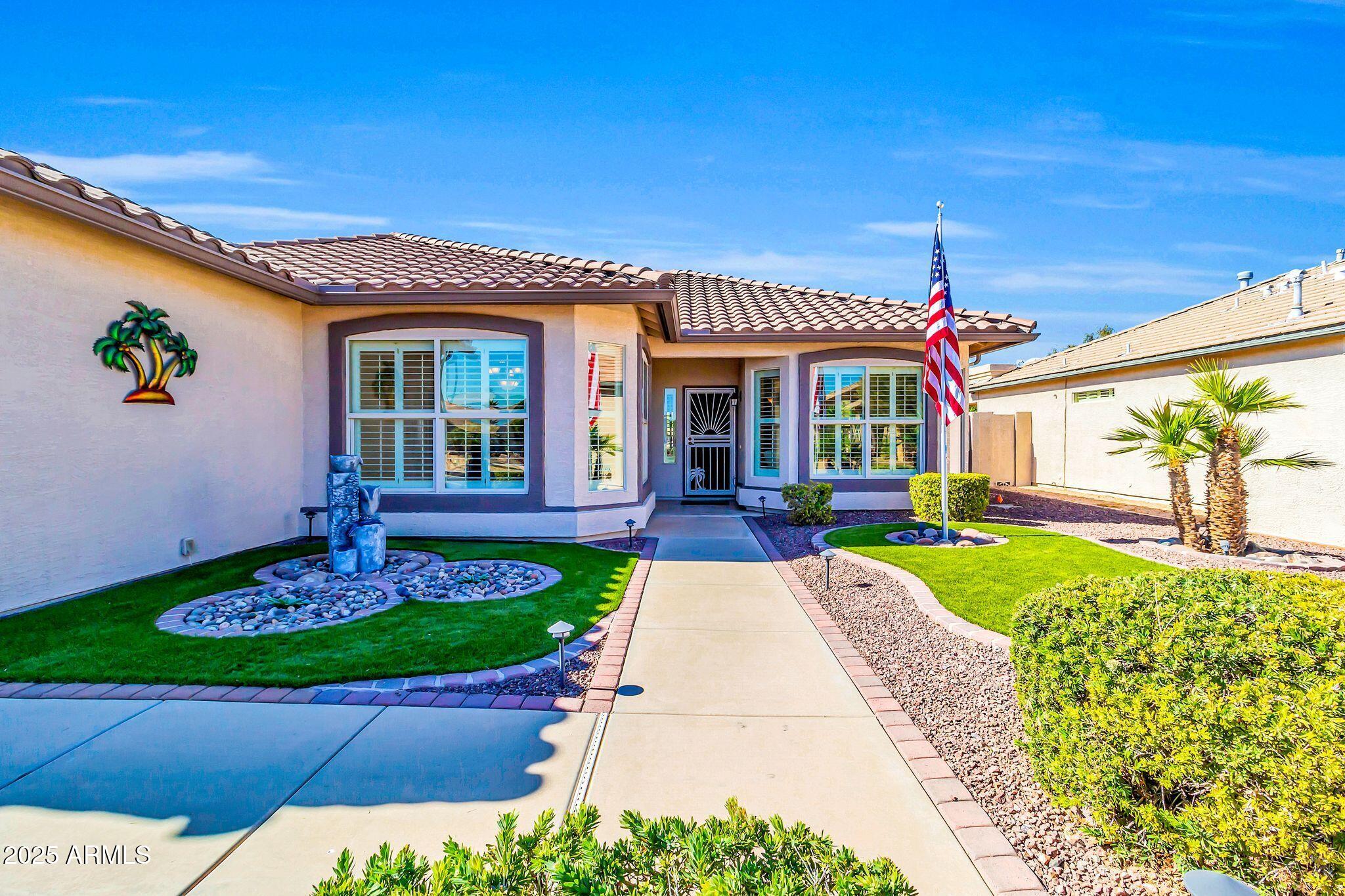 Home exterior with a tiled roof, landscaped walkway, rock gardens, and an American flag.