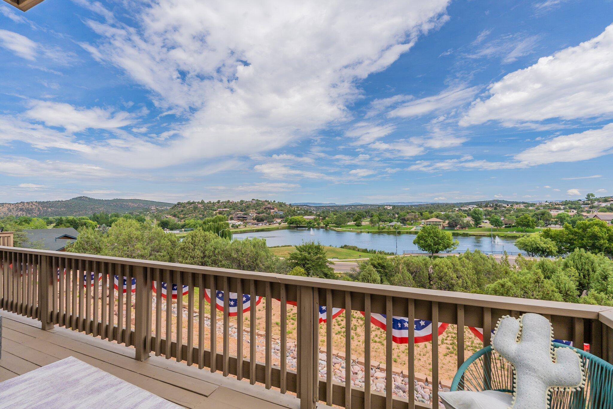 Balcony overlooking a lake and fountain, with distant hills and patriotic bunting on the railing.