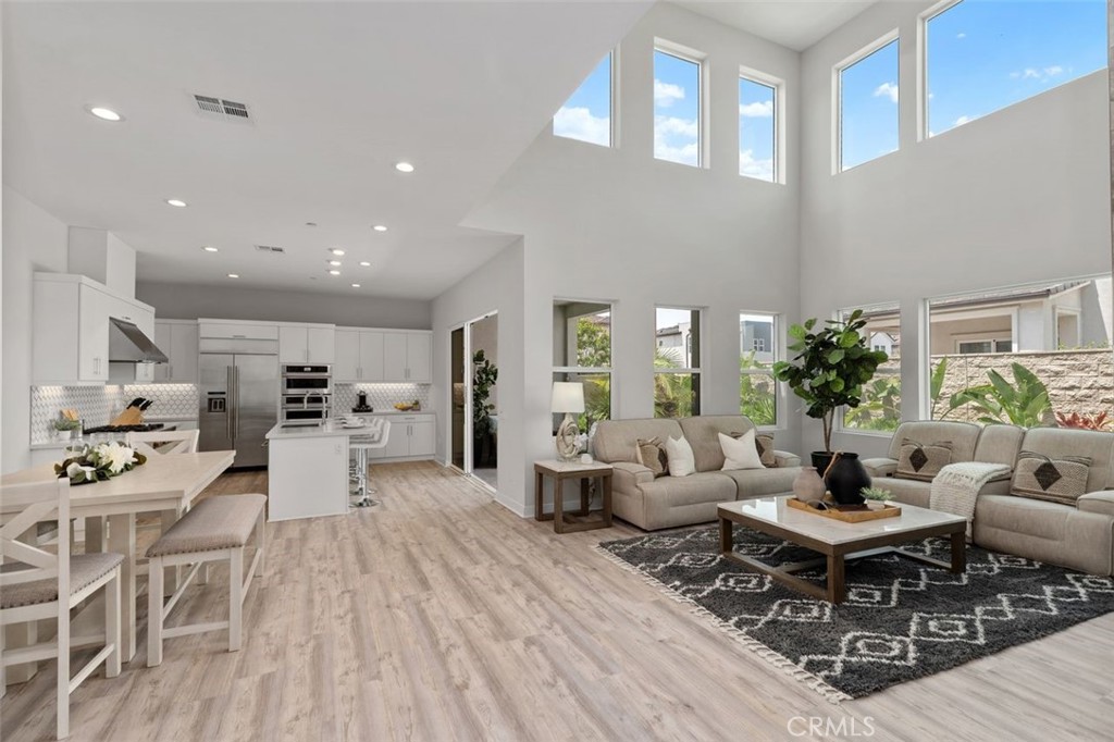 Open-plan living room and kitchen with neutral sofas, white cabinetry, and tall windows.