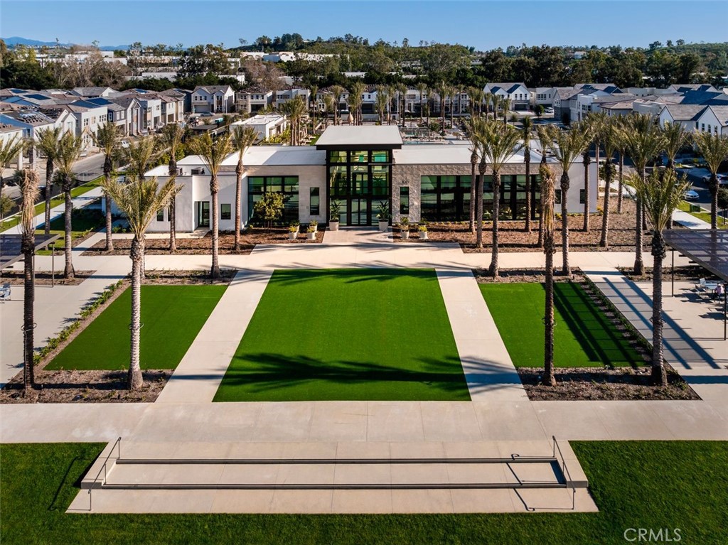Aerial view of a modern community clubhouse framed by palm trees and landscaped lawns.