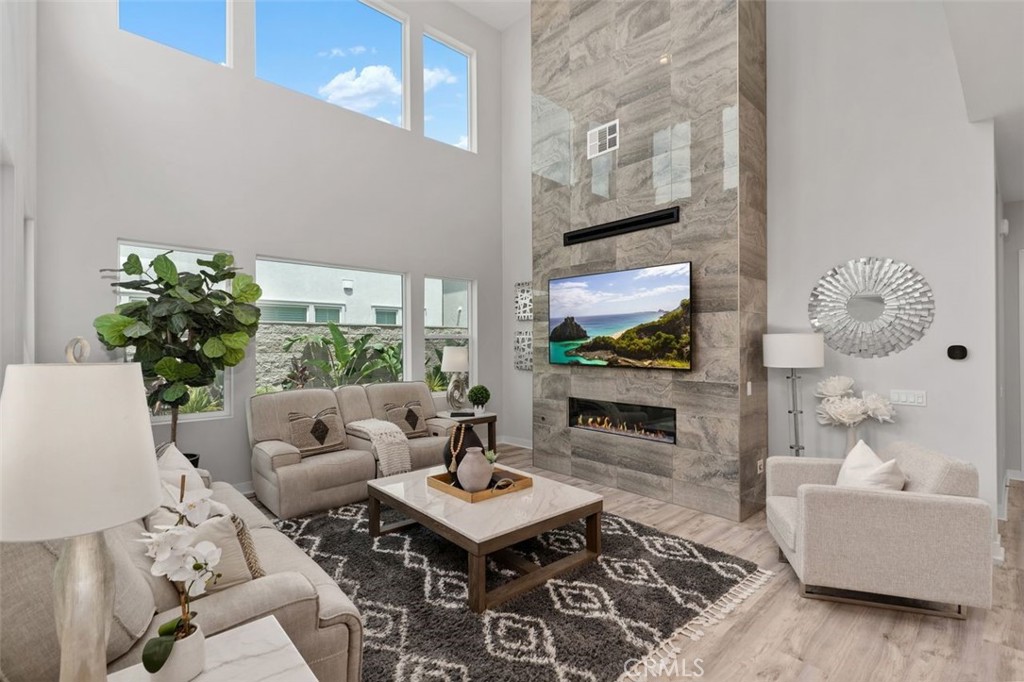 Staged living room with soaring windows and a floor-to-ceiling stone fireplace.