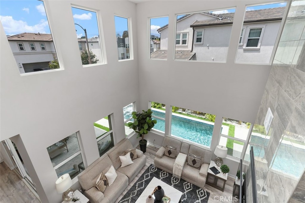 Two-story living room with tall windows overlooking a swimming pool.
