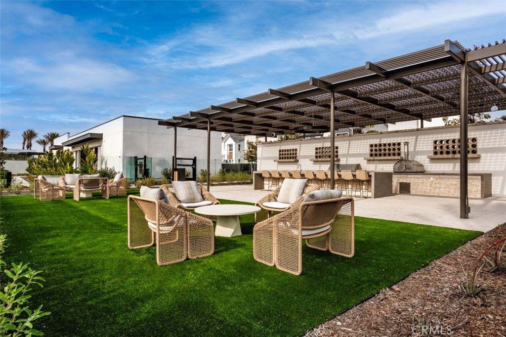 Outdoor patio with pergola, wicker seating, built-in bar, and lawn.