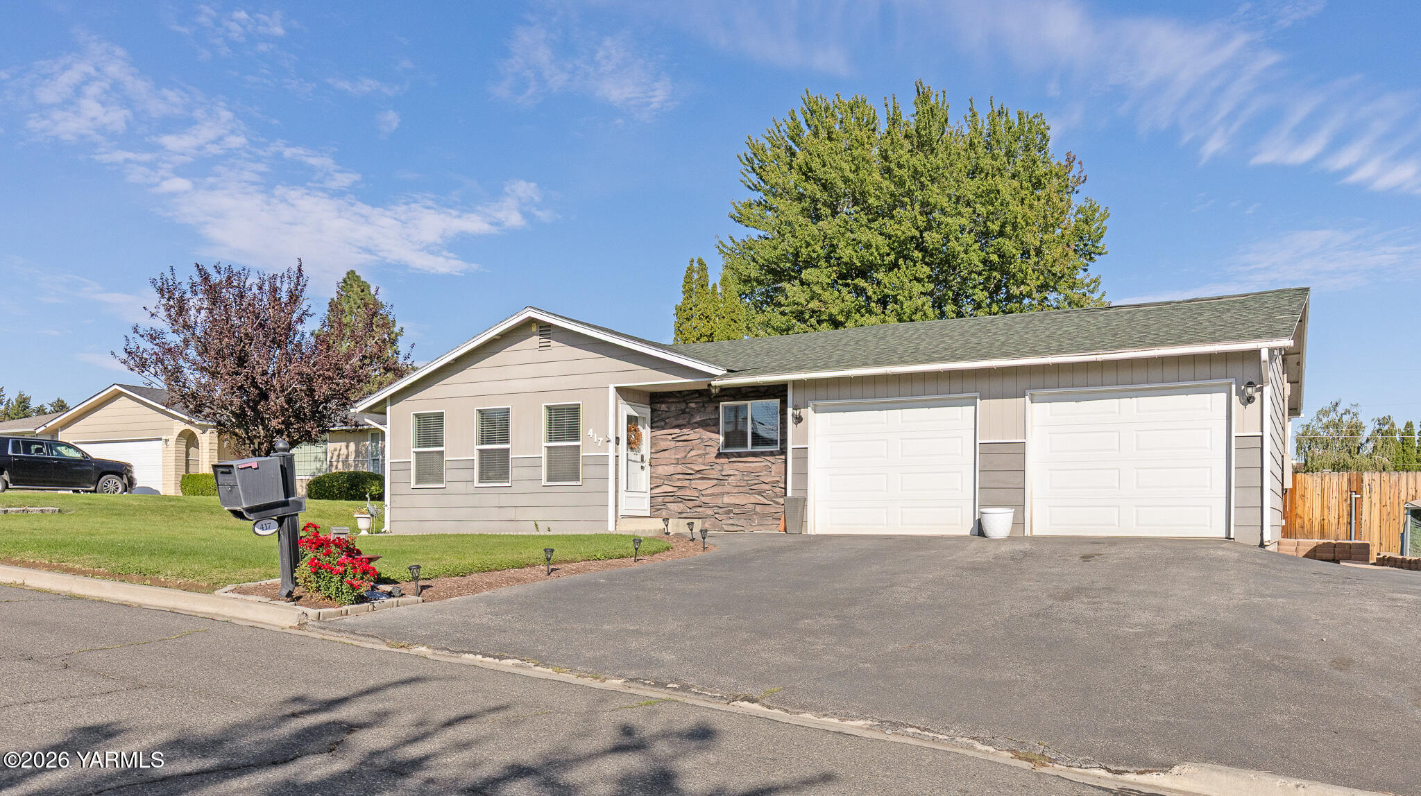 Single-story home with a two-car garage, stone entry accent, and landscaped front lawn.