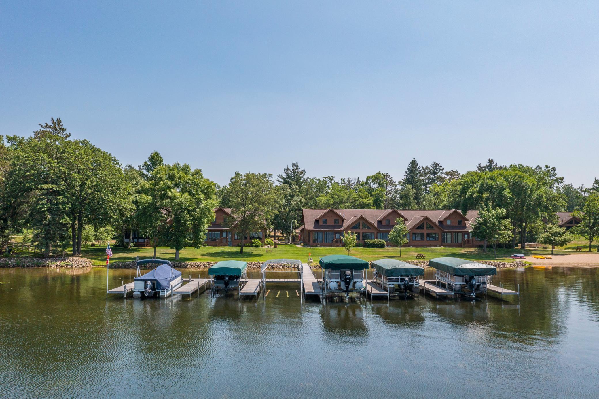 Lakeside lodge-style homes and covered boats lined along docks across the water.