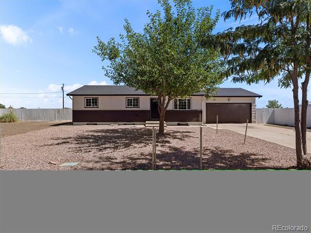 Single-story home with attached garage, gravel front yard, and mature shade trees.