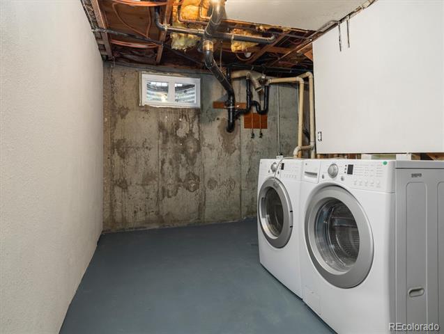 Basement laundry room with front-loading washer and dryer beneath an exposed ceiling.
