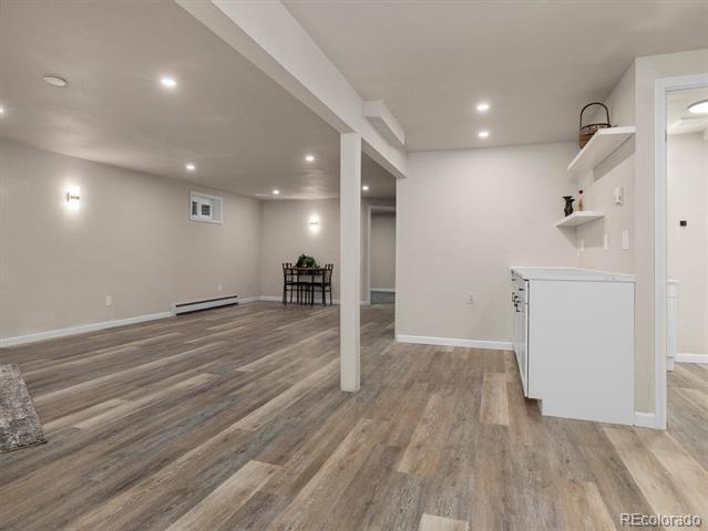 Spacious empty room with plank flooring, a central support column, and a white built-in counter.