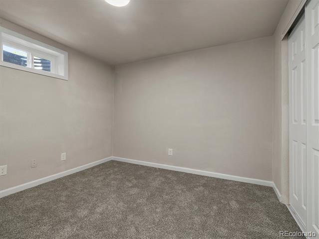 Empty carpeted room with a high horizontal window and a white closet door.