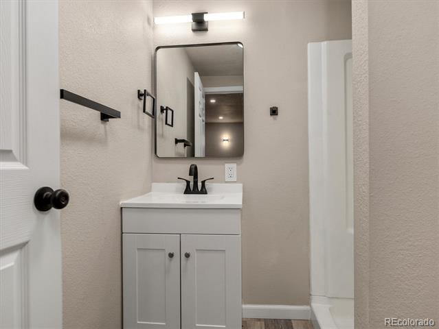 Bathroom vanity with black faucet and hardware, rectangular mirror, and shower enclosure.