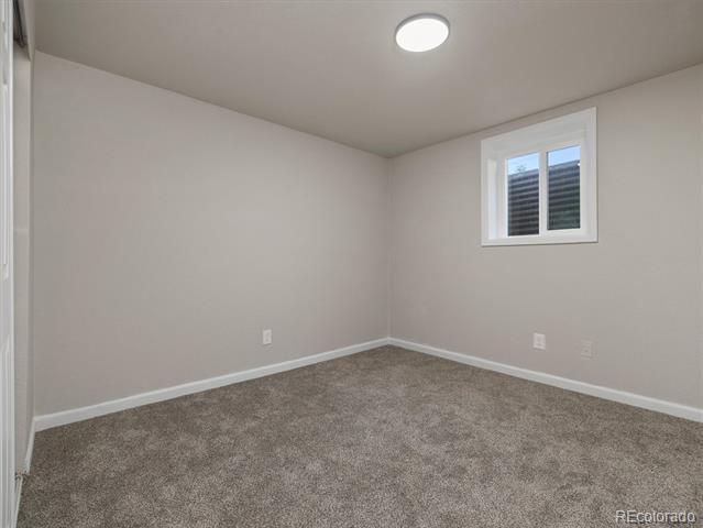 Empty bedroom with gray carpet and a small high-set window.