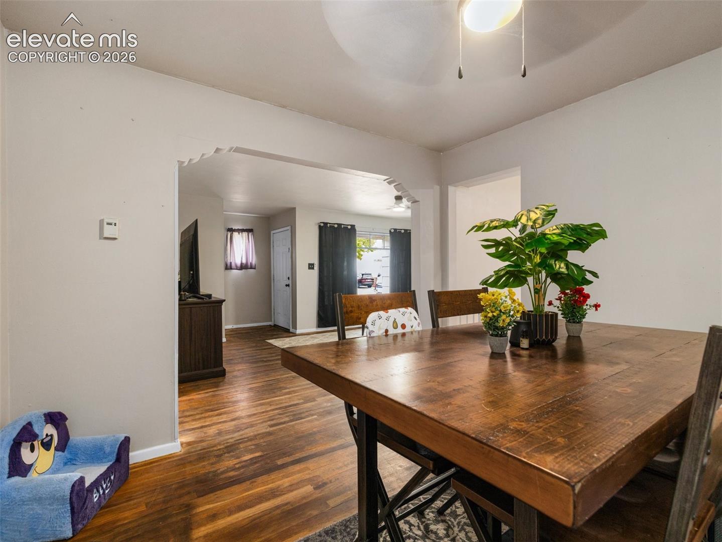 Dining room with a large wooden table and an arched opening to the living area.