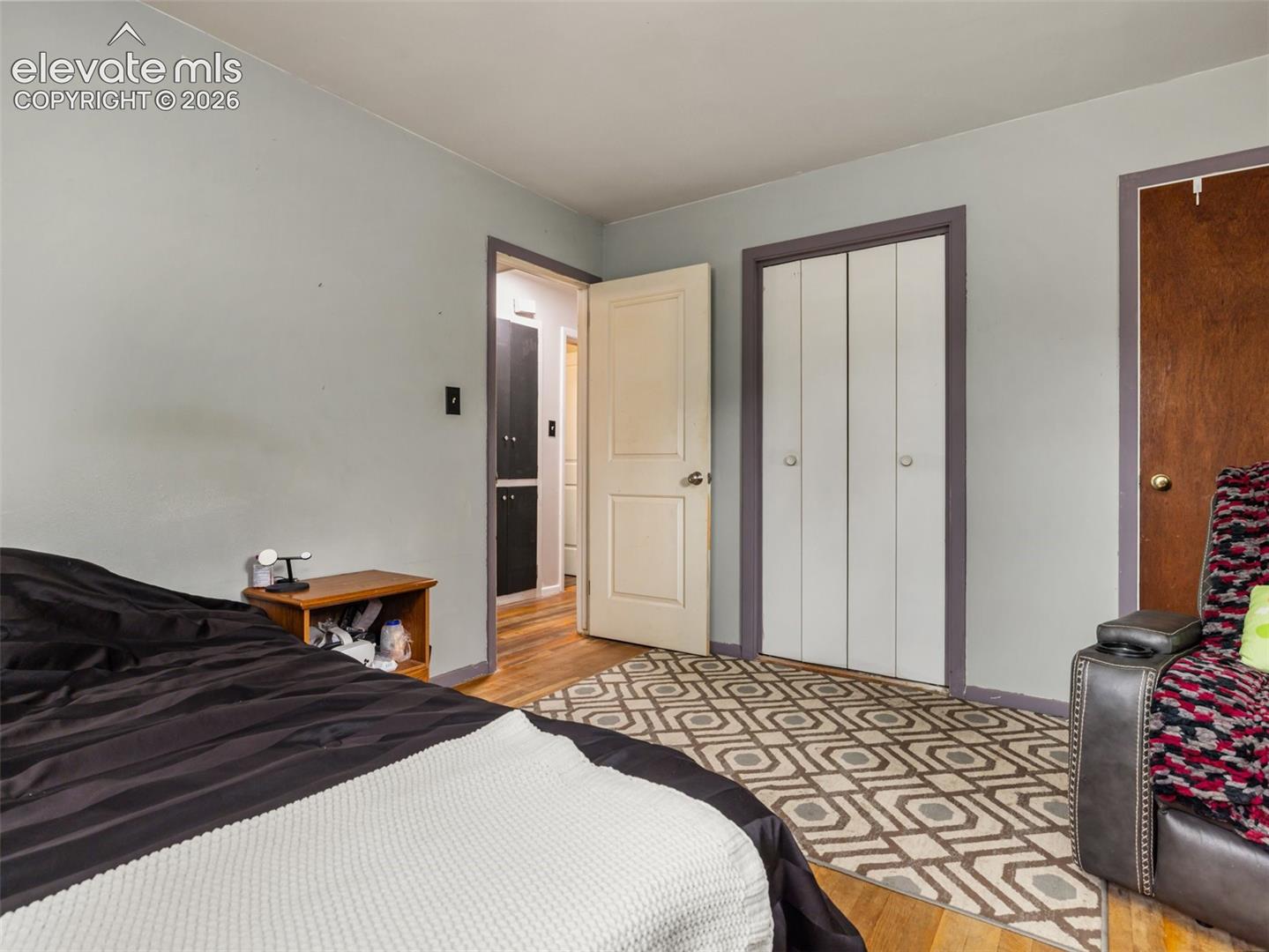 Bedroom with a geometric rug, white double-door closet, and open doorway.