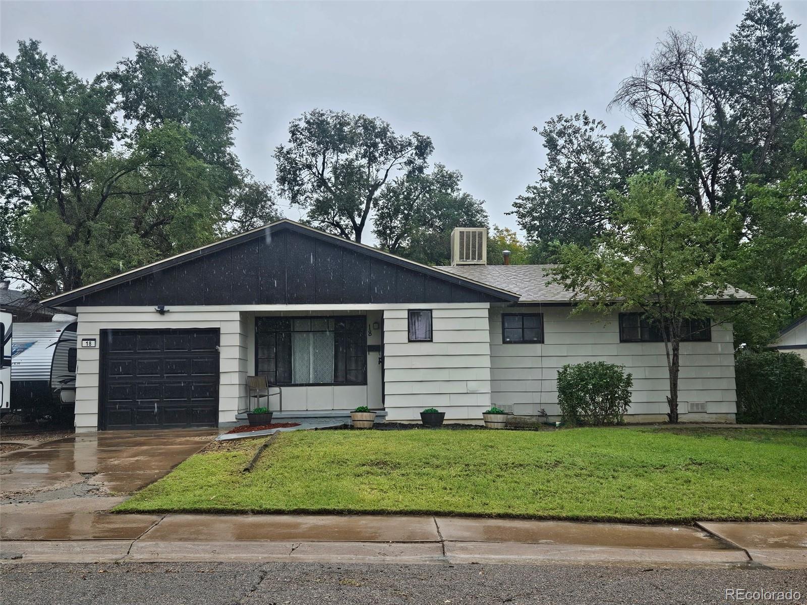 Single-story home with a dark front gable, attached garage, and green lawn.