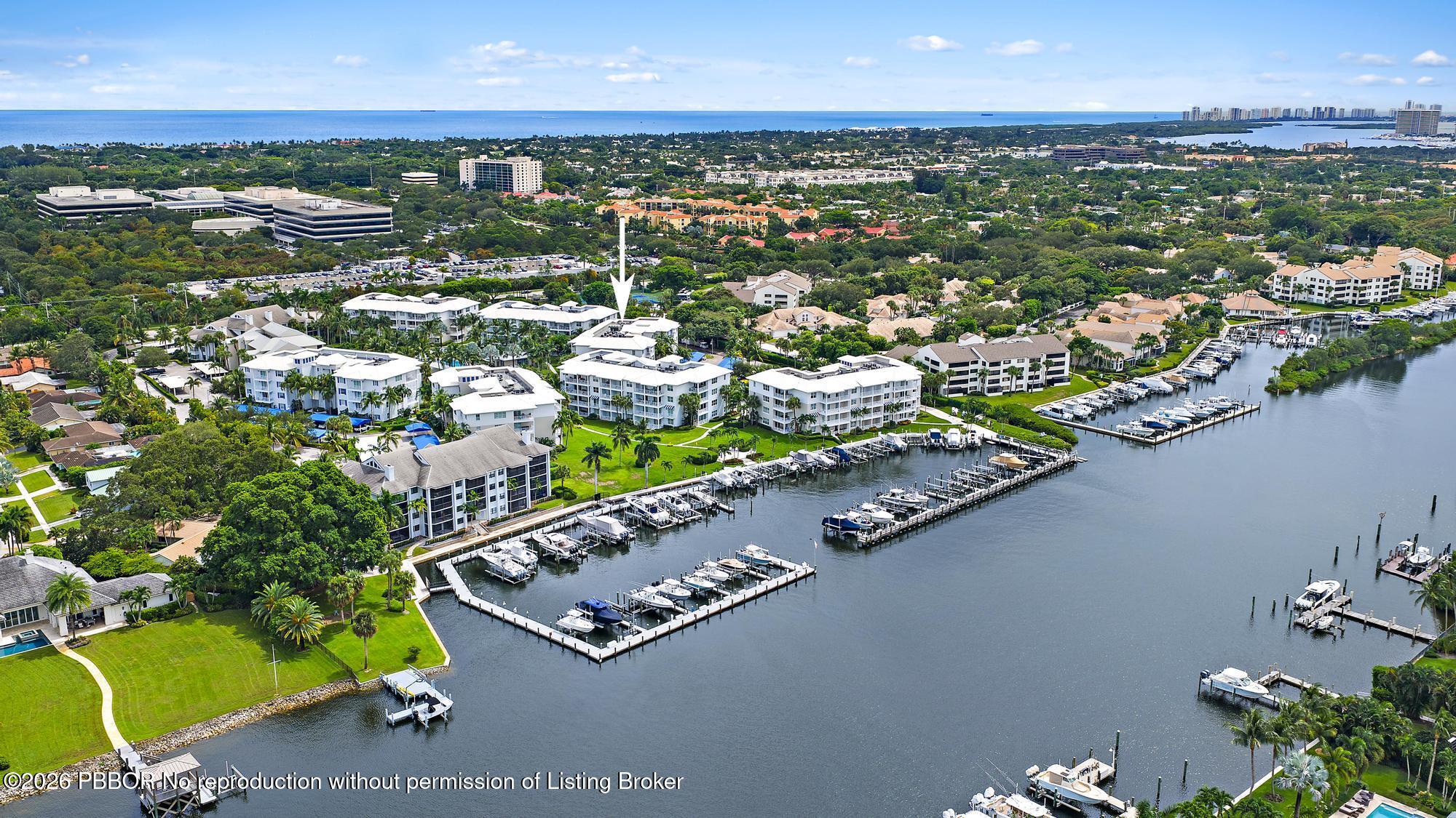 Aerial view of waterfront residences and marina, with an arrow pointing to a building near the docks.