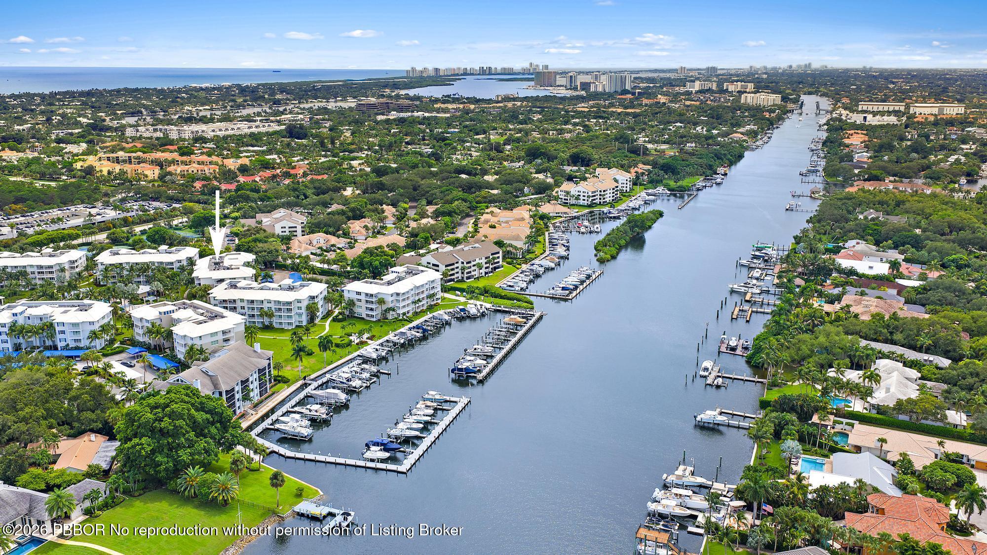 Aerial view of a waterfront community, with an arrow marking a white condo building beside a marina.