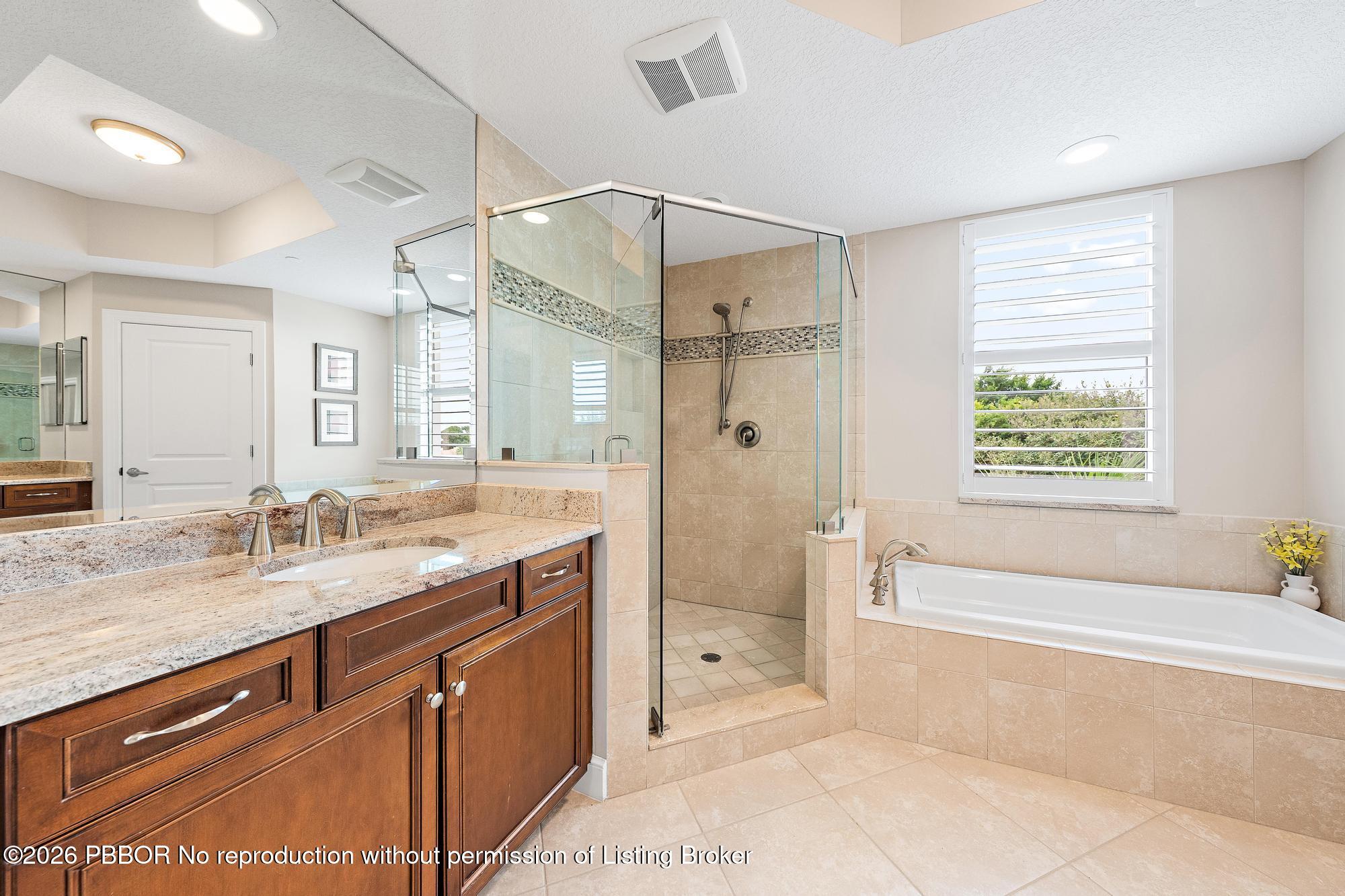 Primary bathroom with glass walk-in shower, soaking tub, and dark wood double vanity.