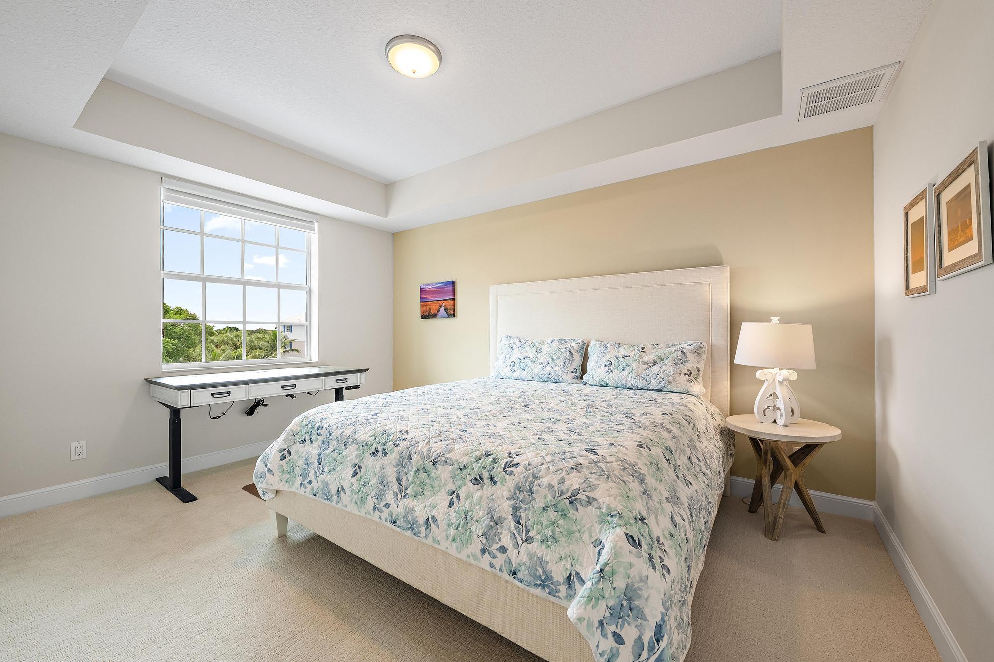 Bedroom with a floral quilted bed and a large window overlooking trees.