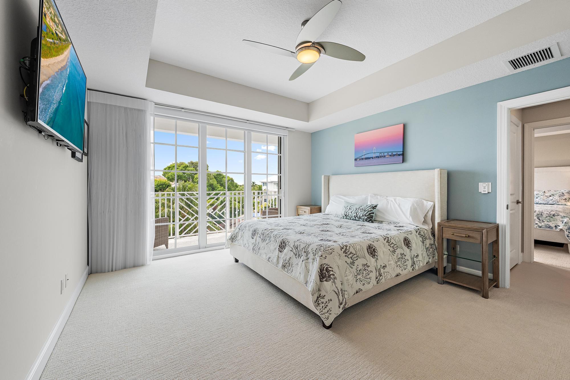 Furnished bedroom with a king-size bed and sliding glass doors opening to a greenery-lined balcony.