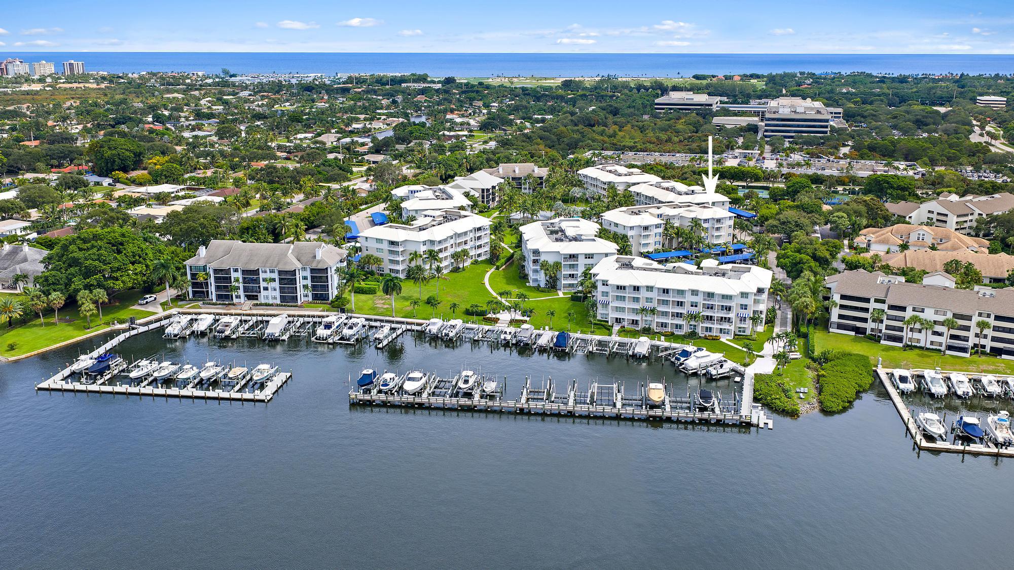 Aerial view of waterfront condominium complex, with the marked building beside a marina and ocean beyond.