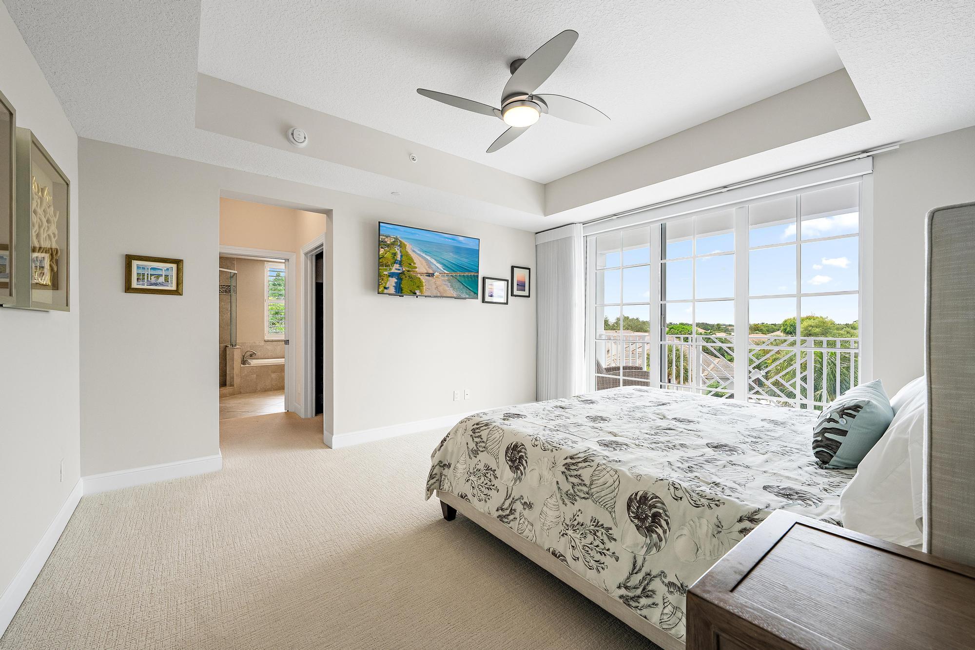 Bedroom with a patterned bedspread and glass doors opening to a balcony.