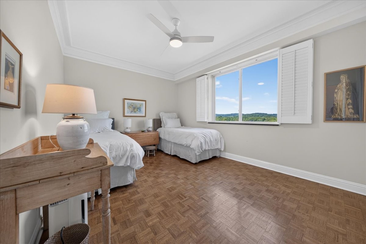 Bedroom with two white beds, parquet flooring, and a large window overlooking green hills.