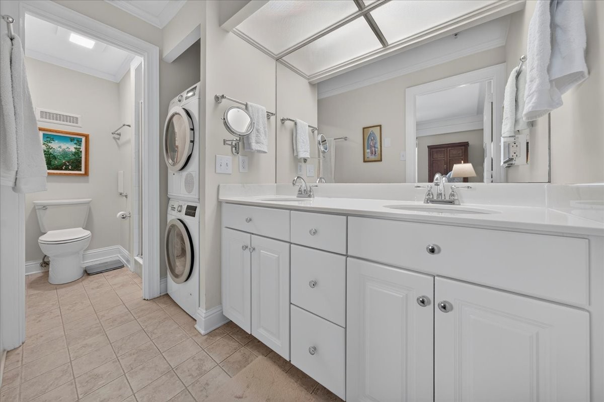 Bathroom with a long double-sink vanity, large mirror, and stacked washer and dryer.