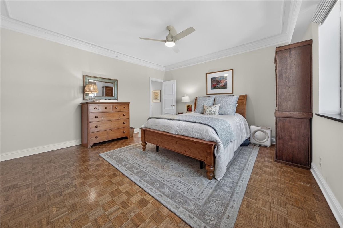 Bedroom with a wooden bed, pale bedding, patterned rug, and parquet floor.