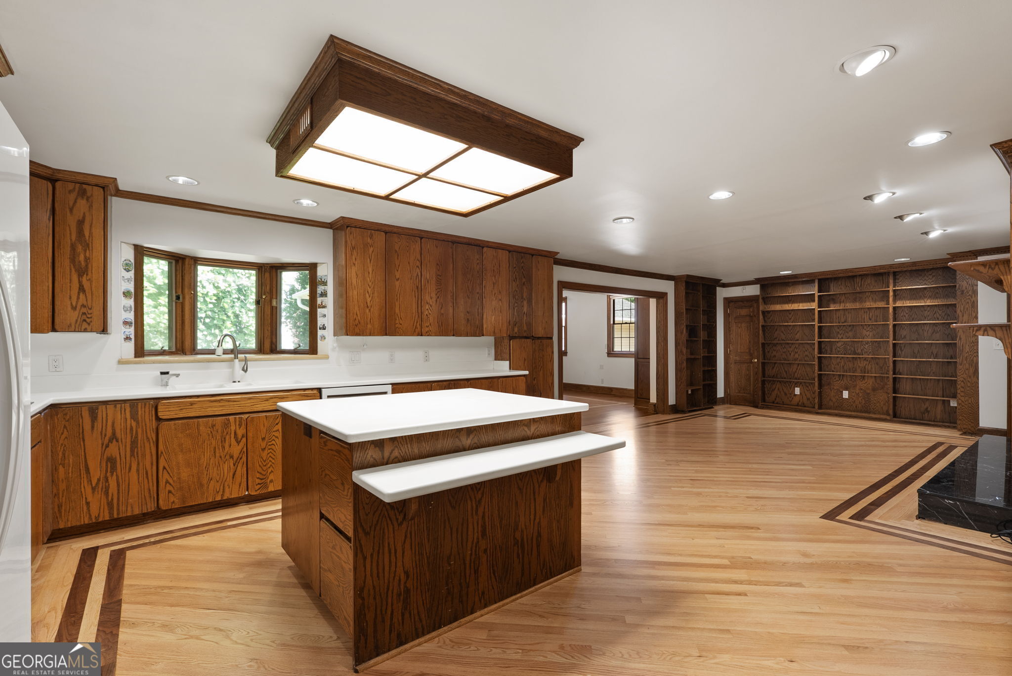 Kitchen with dark wood cabinetry, a central island and bench, and hardwood floors with dark inlaid borders.