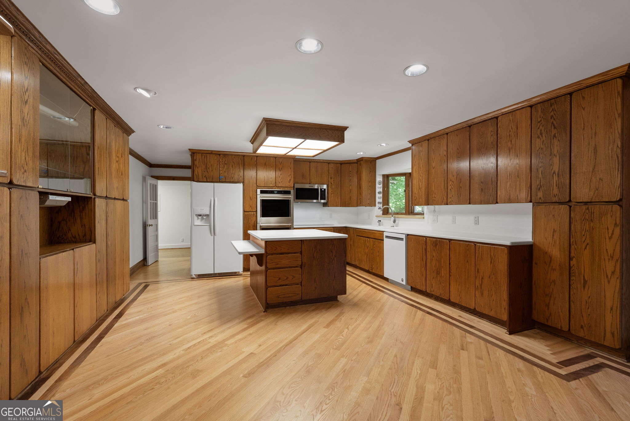 Kitchen with extensive wood cabinetry, a central island, and light wood floors.