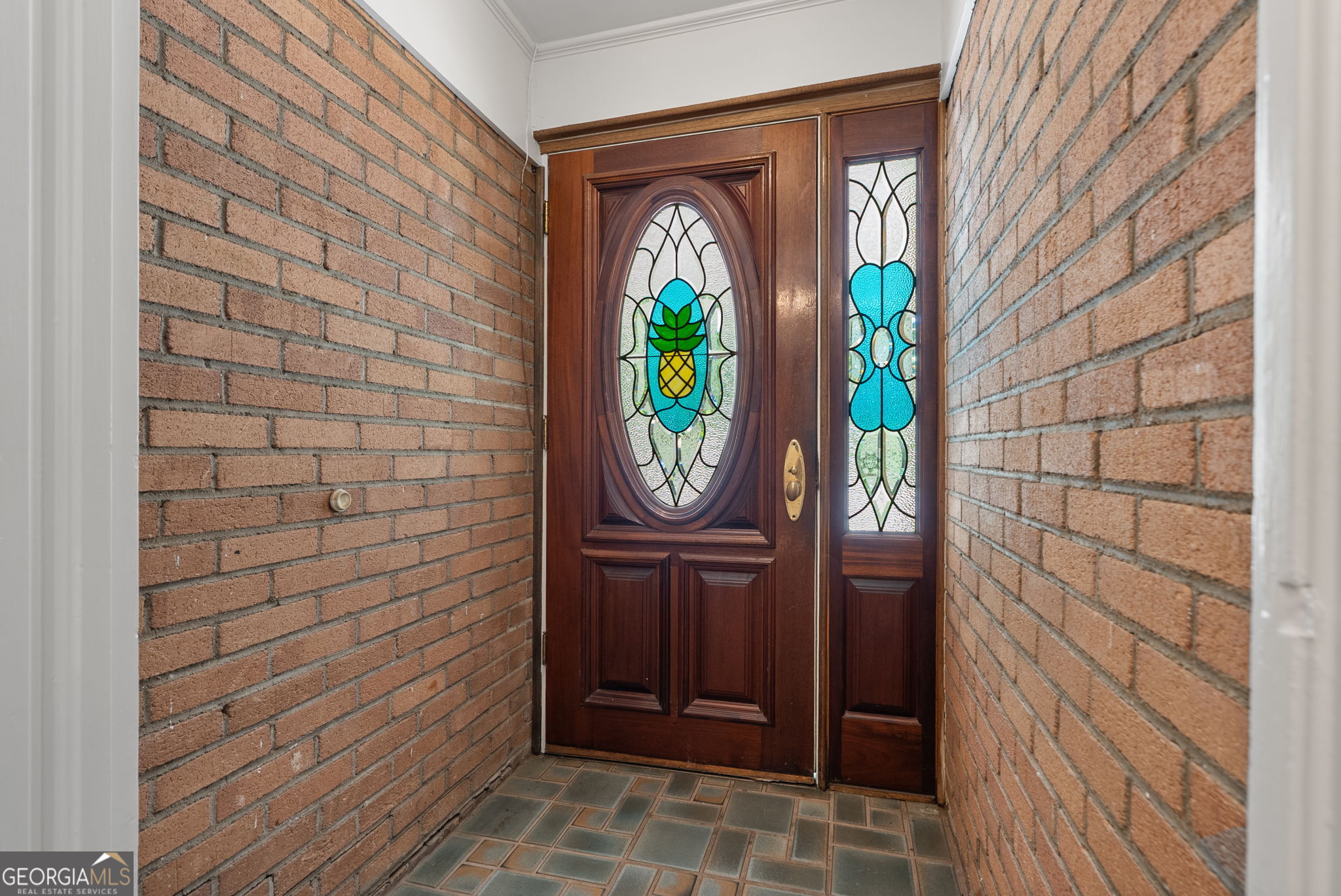Entryway with a wood front door featuring stained-glass pineapple artwork and a matching sidelight.