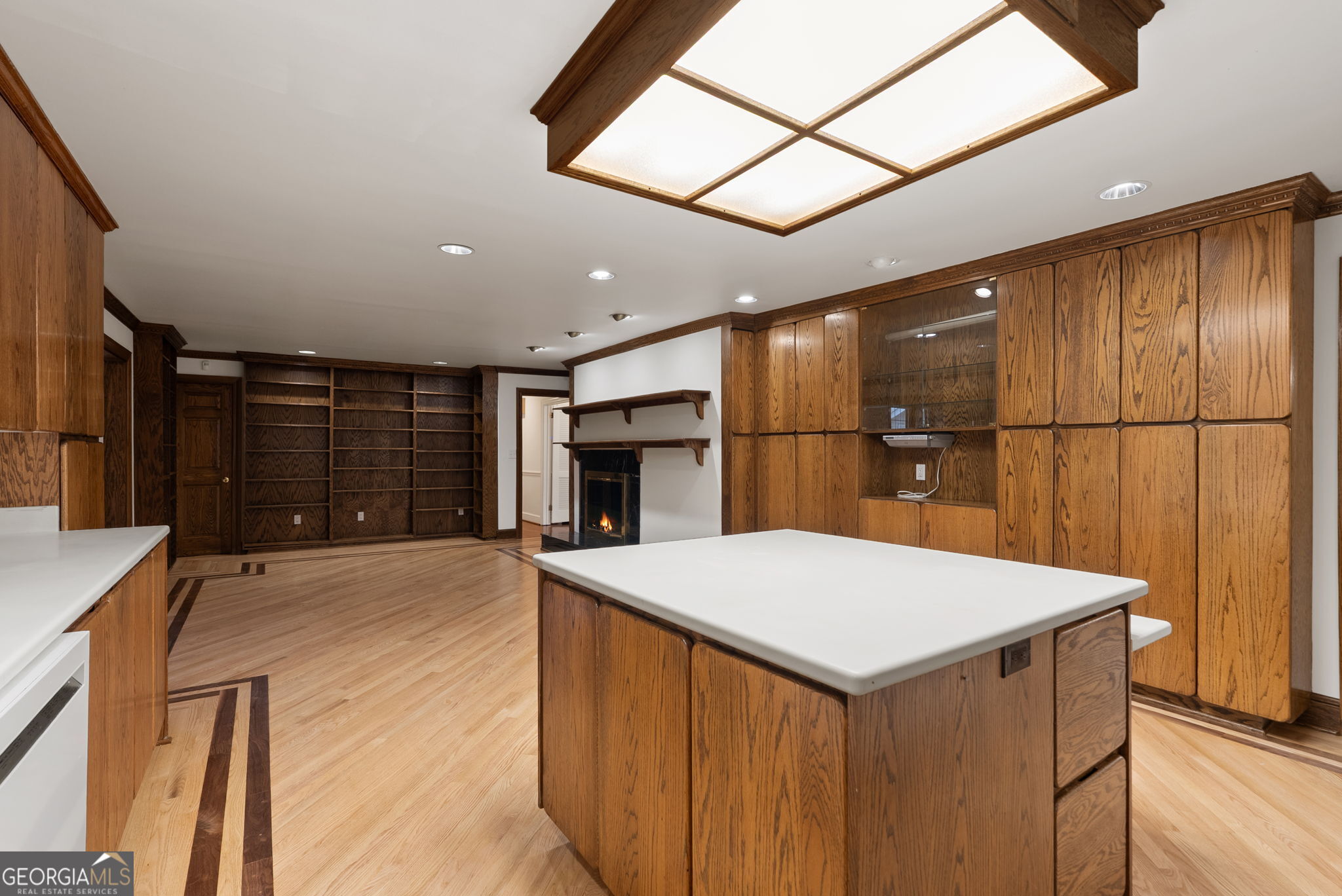 Kitchen with a large white island, extensive wood cabinetry, bookshelves, and a fireplace.