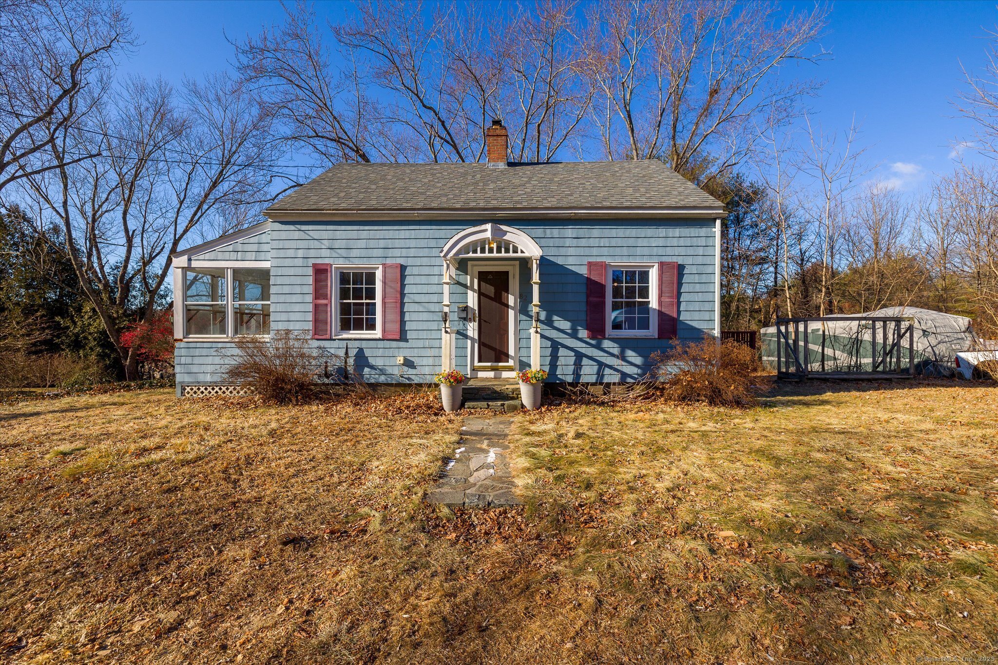 Blue shingle-sided house with red shutters, an arched entry portico, and an enclosed porch.