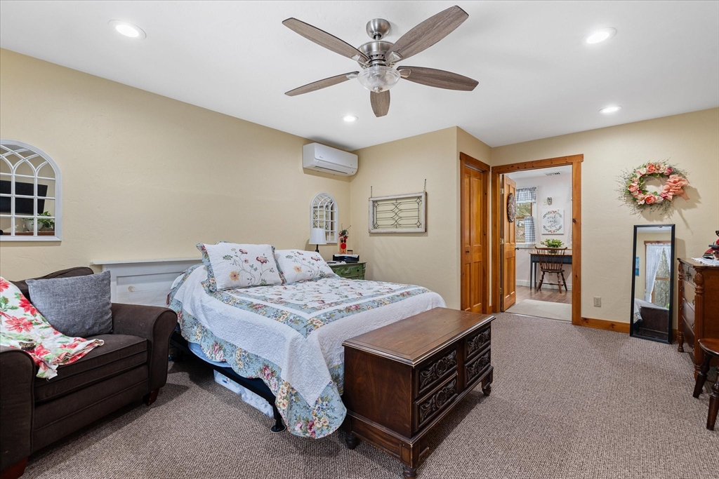 Furnished bedroom with floral bedding, a dark wood chest, and an adjoining sitting area.