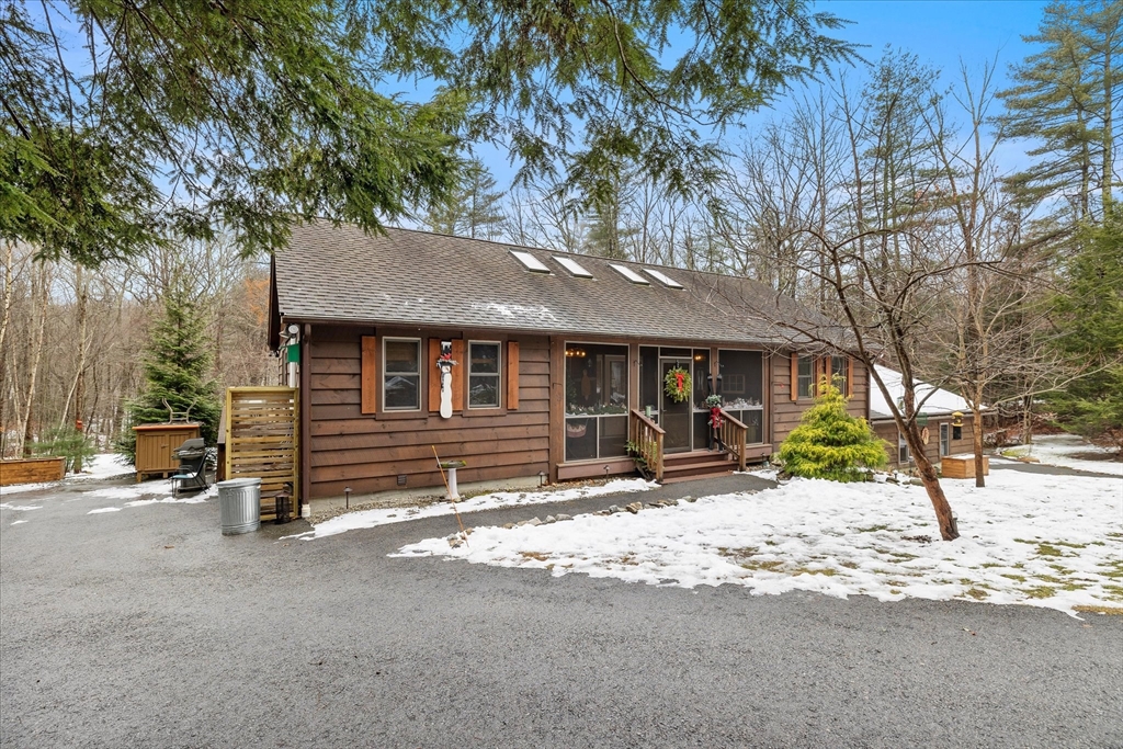 Brown single-story home with skylights and a screened porch, surrounded by patchy snow.