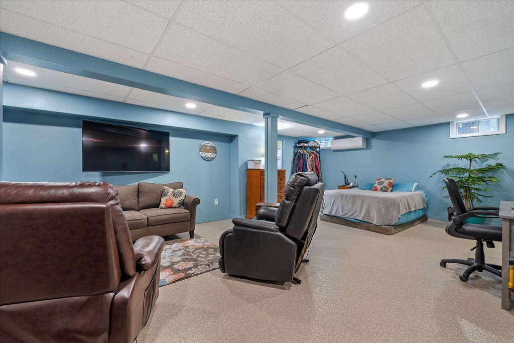 Furnished basement living area with blue walls, a bed, sofas, and a recliner.