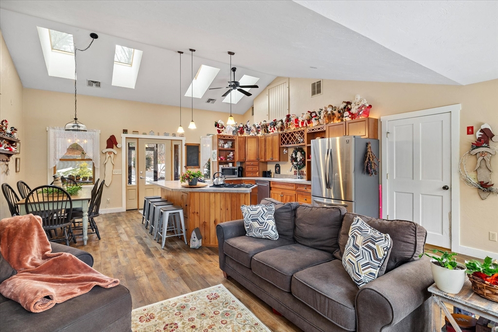 Open-plan kitchen and living area with skylights, a wood island, stainless appliances, and gray seating.