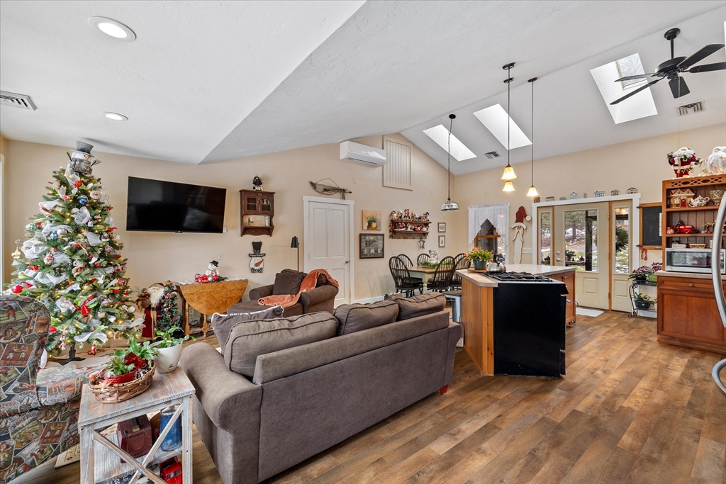 Open-plan living room and kitchen with skylights, wood floors, and a decorated Christmas tree.