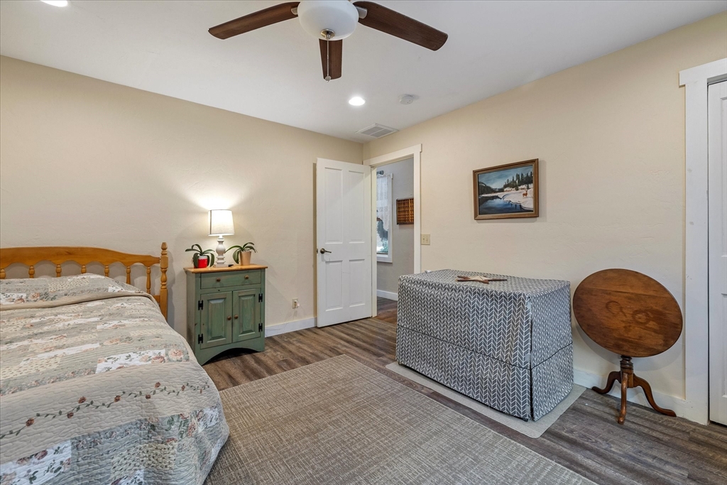 Bedroom with a floral quilt, green bedside cabinet, and patterned storage bench.
