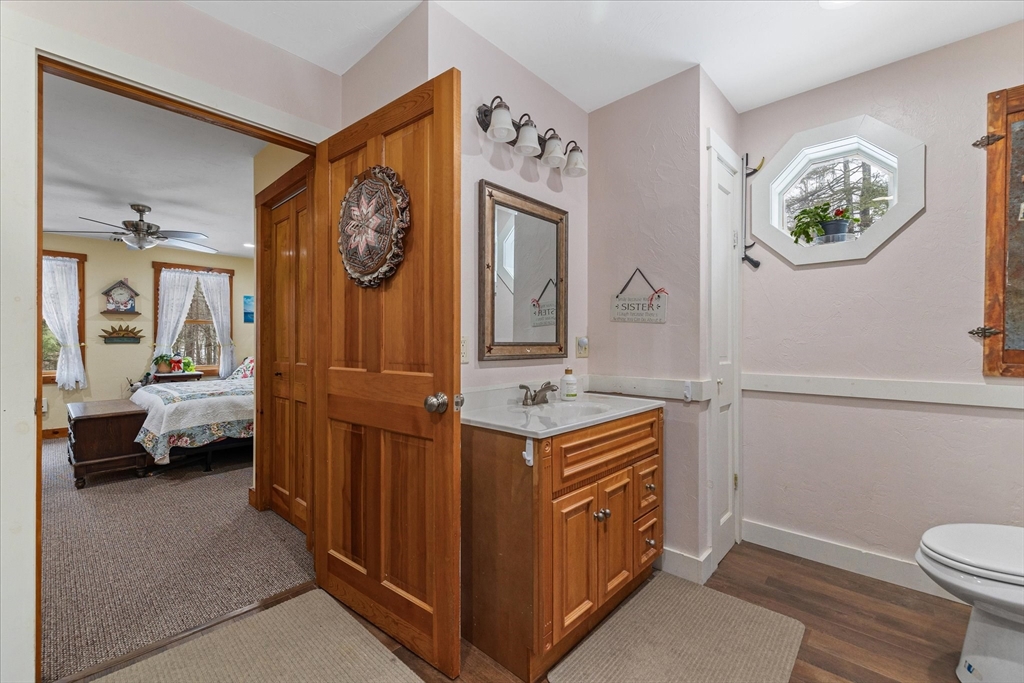 Bathroom with a wood vanity and octagonal window, opening onto a bedroom.