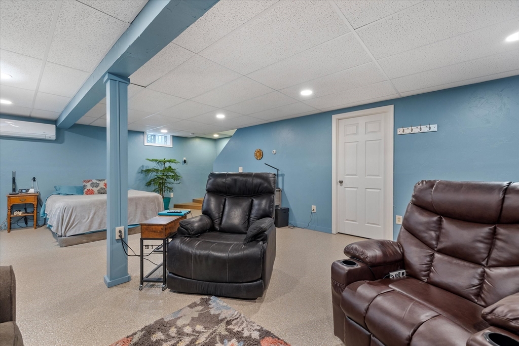 Furnished basement with blue walls, a bed, and two brown leather recliners.