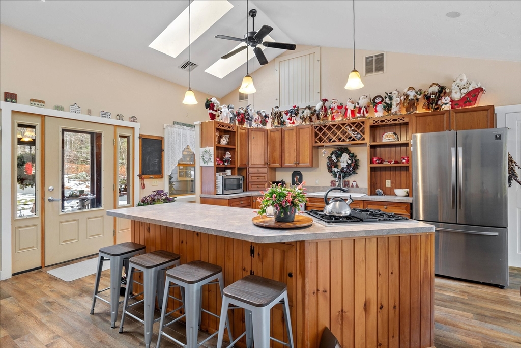 Kitchen with a large wood-paneled island, stainless steel refrigerator, and holiday decorations above the cabinets.