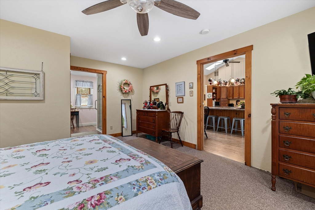 Bedroom with a floral quilted bed, wood-trimmed doorways, and a ceiling fan.