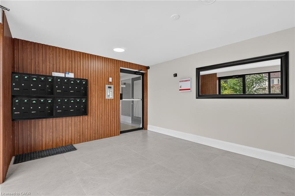 Lobby with black mailboxes on a wood-paneled wall and a glass entry door.