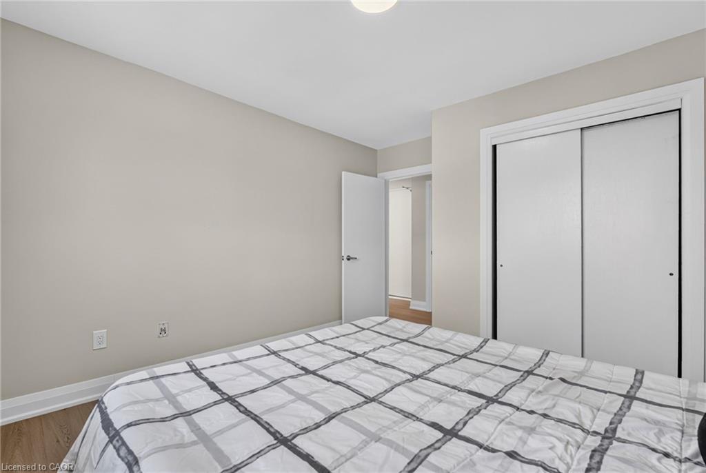 Bedroom with a gray-and-white plaid bedspread and white sliding closet doors.